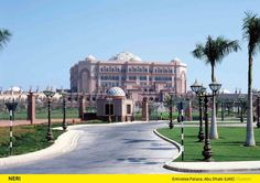 a large building sitting on the side of a road with palm trees in front of it