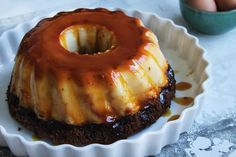 a chocolate cake covered in caramel sauce on top of a white plate next to an egg