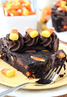 a piece of chocolate cake with candy corn on it and a fork next to it