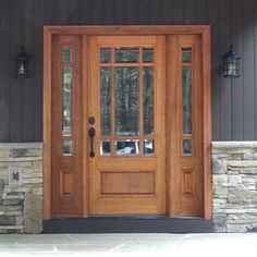 the front door to a house with stone pillars and glass panels on it's sides