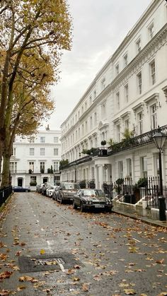 an empty street with cars parked on the side and trees lining the road in front