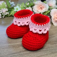 a pair of red crocheted baby booties sitting on top of a wooden table