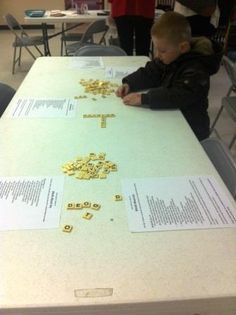 a young boy sitting at a table playing with letters