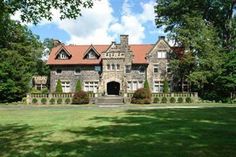 a large stone house surrounded by trees and grass