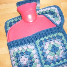 a blue crocheted pot holder with a pink plastic cup on top of it