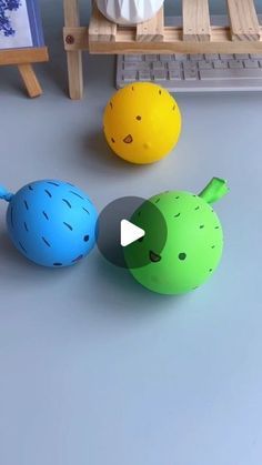 three different colored balls sitting on top of a table next to an easel and chair