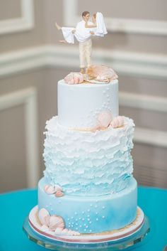 a blue and white wedding cake with a bride and groom figurine on top