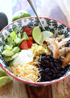 a bowl filled with black beans, rice and avocado on top of a wooden table