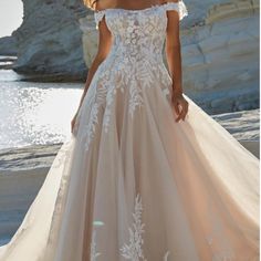 a woman in a wedding dress standing on the beach with her hand on her hip