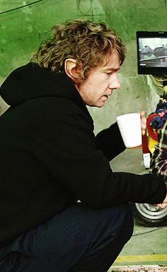 a man holding a coffee cup in front of a television screen with the image of a motorcycle on it