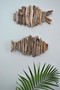 two pieces of driftwood sitting on top of a white wall next to a green plant