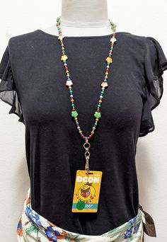 a woman wearing a black shirt and multicolored beaded necklace with an id tag