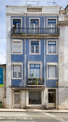 a blue and white building with balconies on the top floor, next to a street