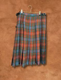 Preloved and Preworn This vintage traditional kilted skirt is custom-made from lightweight 10 oz tartan fabric, featuring 3/4 inch pleating at the back for that classic kilt swing. With two buckled straps on one side and one on the inside, this gorgeous piece is a classic design never goes out of style! 100% Pure New Wool Made at the Lochcarron mill in the heart of the Scotland. Artwork by artist Christopher Porter Waist 32-34” Hips 42” Length 27” If you are expecting a “new” perfect piece, thes Fall Scottish Pleated Skirt, Scottish Style Fitted Pleated Skirt For Fall, Fitted Scottish Pleated Skirt, Classic Pleated Plaid Skirt, Fitted Full Skirt In Plaid, Fitted Pleated Plaid Skirt, Scottish Style Pleated Skirt For Fall, Scottish Style Plaid Lined Skirt, Scottish Plaid Pleated Bottoms