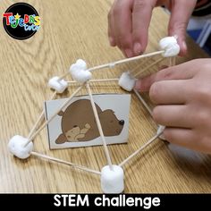 a child is making a craft with marshmallows and cotton balls on a stick