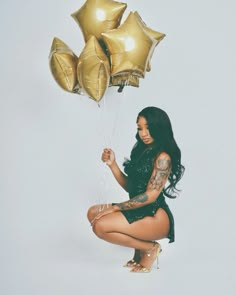 a woman holding some gold balloons and posing for the camera with her leg up in the air