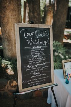 a chalkboard sign that says taco'bouta wedding standing next to a table