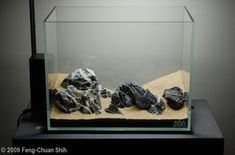 an aquarium filled with rocks and gravel on top of a black table next to a wall