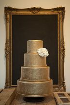 a three tiered cake sitting on top of a wooden table next to a framed photo