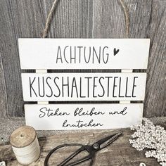 a wooden sign that says achtung kusshalestelle with scissors and spools