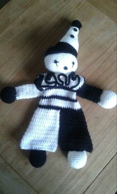 a crocheted doll is sitting on a wooden table with a black and white hat