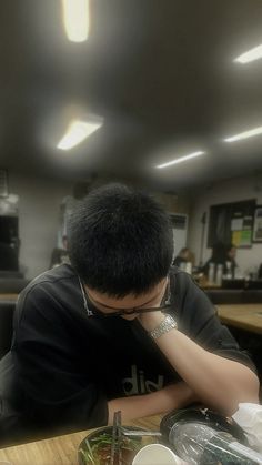 a man sitting at a table with food in front of him and his head on his hands