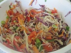 a white bowl filled with coleslaw, carrots and sprouts on top of a table