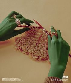 a woman is knitting yarn with her hands and wearing green gloves while holding a pair of scissors