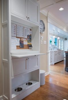 an open kitchen with white cabinets and drawers on the wall next to a wooden floor