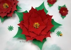 red paper flowers with green leaves on white surface