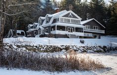 a large house in the middle of winter with snow on the ground and trees around it