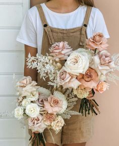 a woman wearing overalls holding a bouquet of flowers