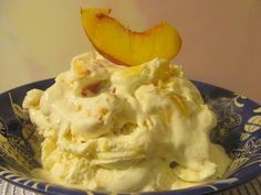 a blue bowl filled with ice cream next to a slice of peach on top of a table