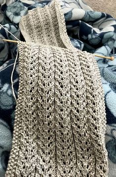 a close up of a knitted sweater on a bed with blue and white floral bedspread