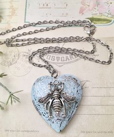 "Large Honey Bee Locket Necklace, Honey Bee Jewelry, Honey Bee Long Necklace nature jewelry, garden necklace Heart shaped locket with a floral engraved design, embellished with a Little Honey Bee. The locket is stainless steel with a Silver and Blue finish on the front and plain silver on the back. It measures about 1.5 inches across the top and opens with two sections inside to hold special photos or mementos. The sparkly chain is 24\" with a lobster clasp. Thanks so much for stopping by. Feel Vintage Personalized Jewelry As Gift For Her, Personalized Vintage Jewelry As Gift For Her, Antique Charm Necklace With Lobster Clasp As Gift, Antique Jewelry With Lobster Clasp For Gift, Nature-inspired Heart Shaped Jewelry Gift, Blue Vintage Charm Jewelry Gift, Vintage Locket Jewelry Gift For Her, Vintage Locket Jewelry As A Gift For Her, Vintage Locket Jewelry As Gift For Her