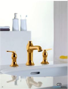 two golden faucets sitting on top of a white sink