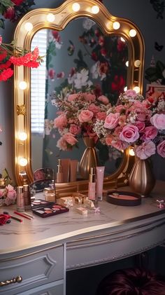 a vanity with flowers and lights on it in front of a mirror that is lit up