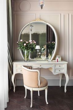 a dressing table with a mirror and flowers on it