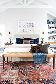 a large bed sitting in the middle of a room with lots of pillows on top of it