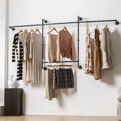 there are many clothes hanging on the rack in this room, including sweaters and pants