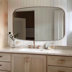 a bathroom vanity with a large mirror above it and two vases on the counter