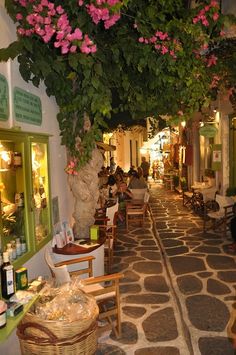 an alley way with tables and chairs lined up on both sides, surrounded by greenery