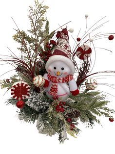 a christmas arrangement with a snowman, candy canes and greenery on a white background