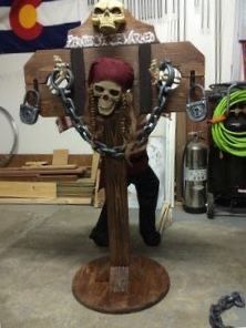 a wooden chair that has a skeleton on it with chains attached to the back and arms