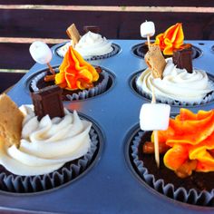 four cupcakes with marshmallows, orange and brown decorations on them