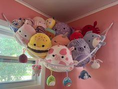 many stuffed animals are hanging from the ceiling in a room with pink walls and windows