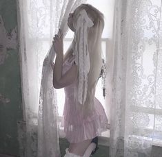 a woman with long blonde hair is standing in front of a window wearing white boots