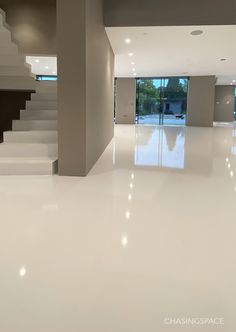 an empty room with white floors and stairs