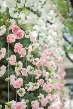 pink carnations hanging from strings in front of trees