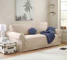 a living room with a white couch and blue throw pillows on the back of it